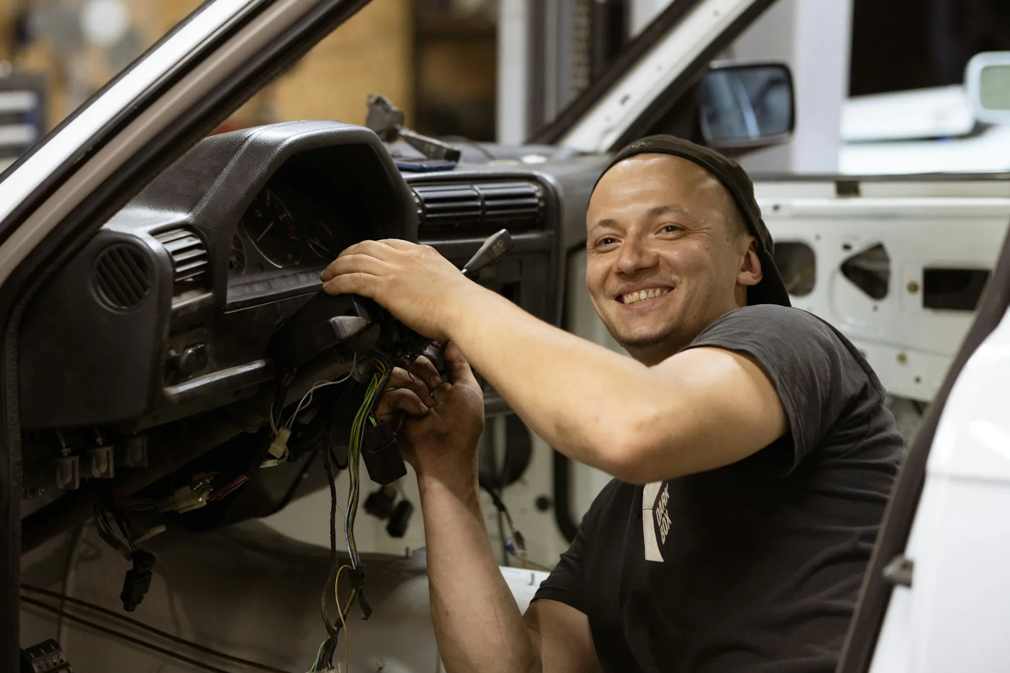 Technician working under the dashboard of a car and smiling