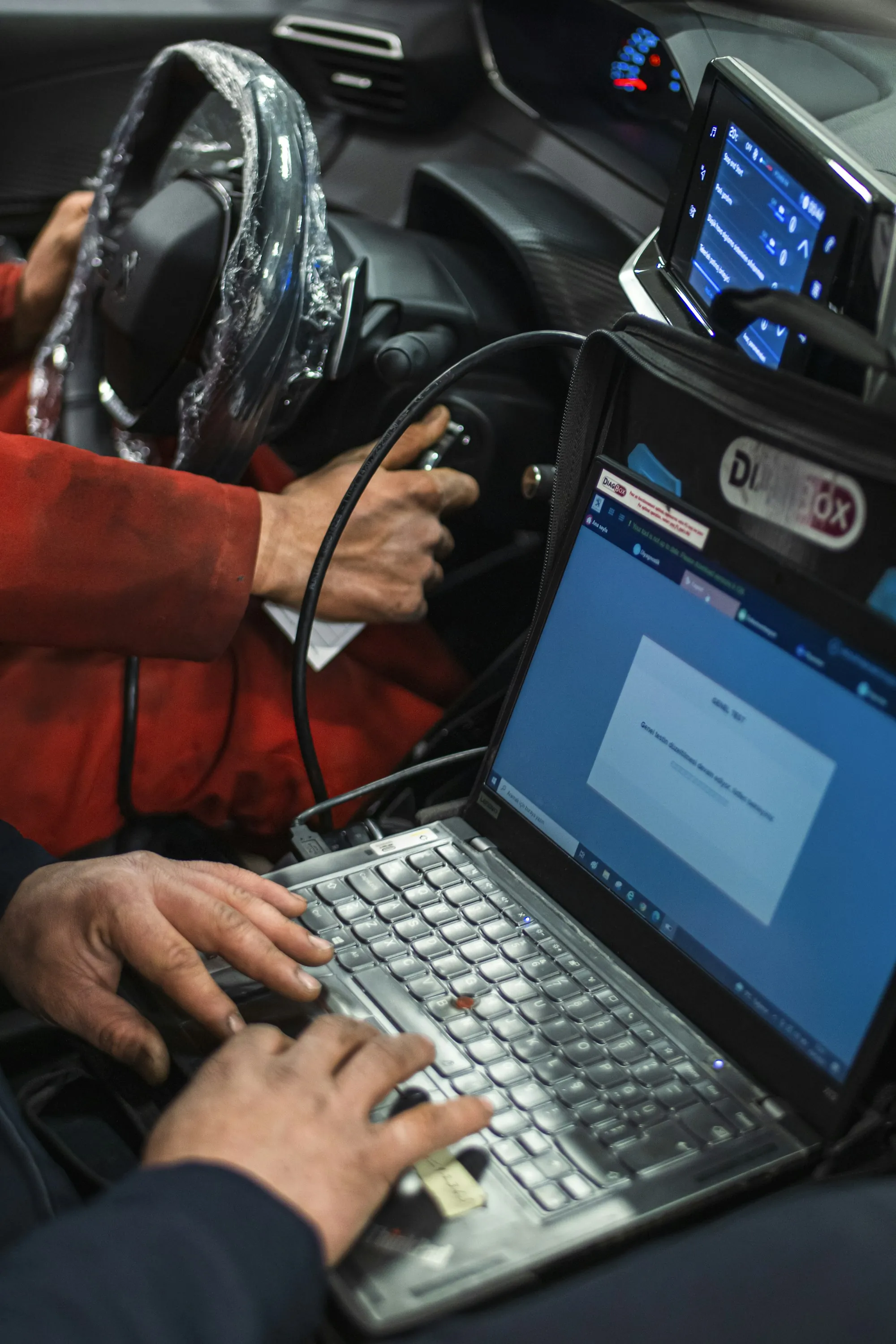 Diagnostic laptop connected to a vehicle on the driver's seat