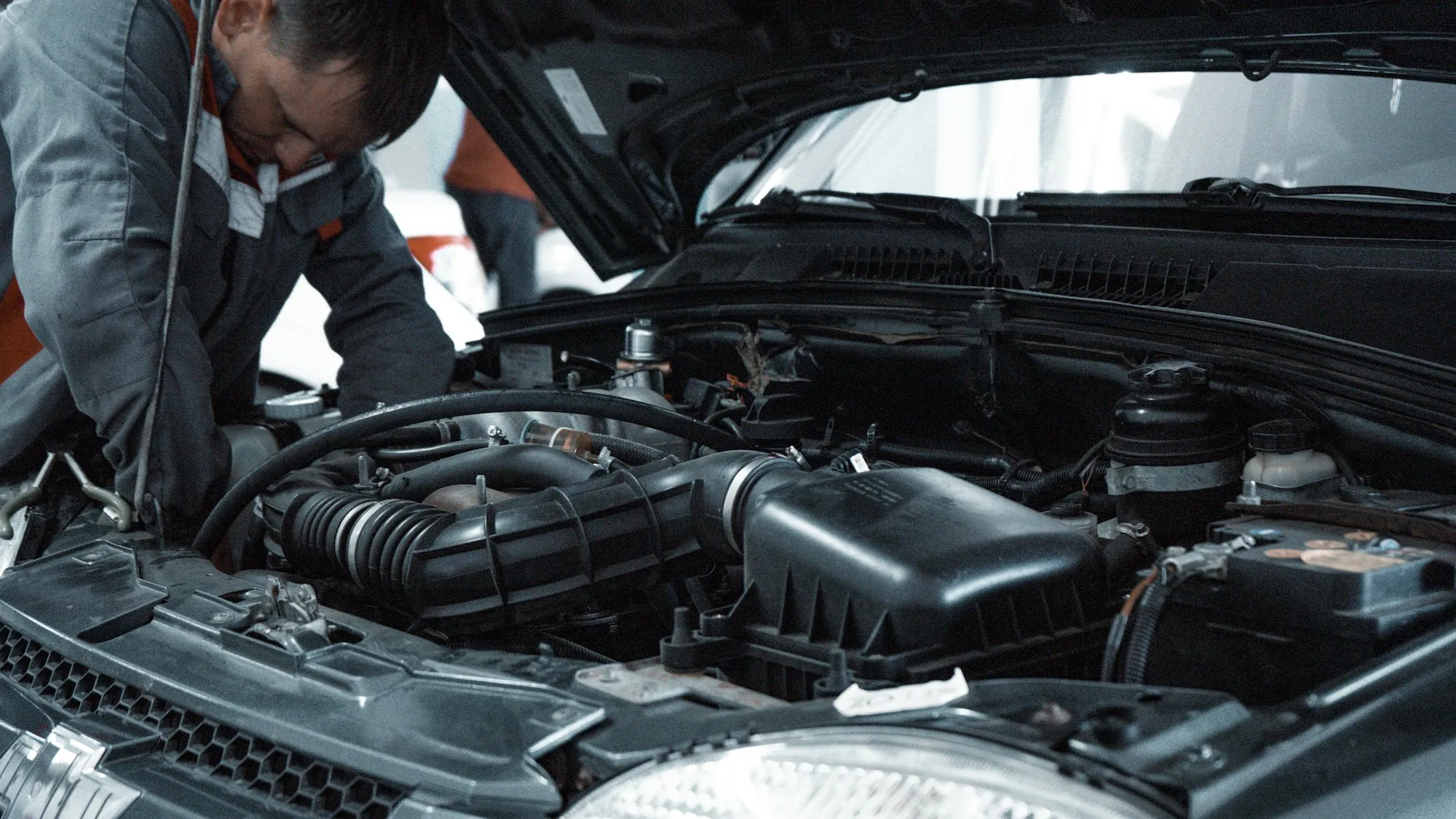 Mechanic leaning into the engine bay of a raised car