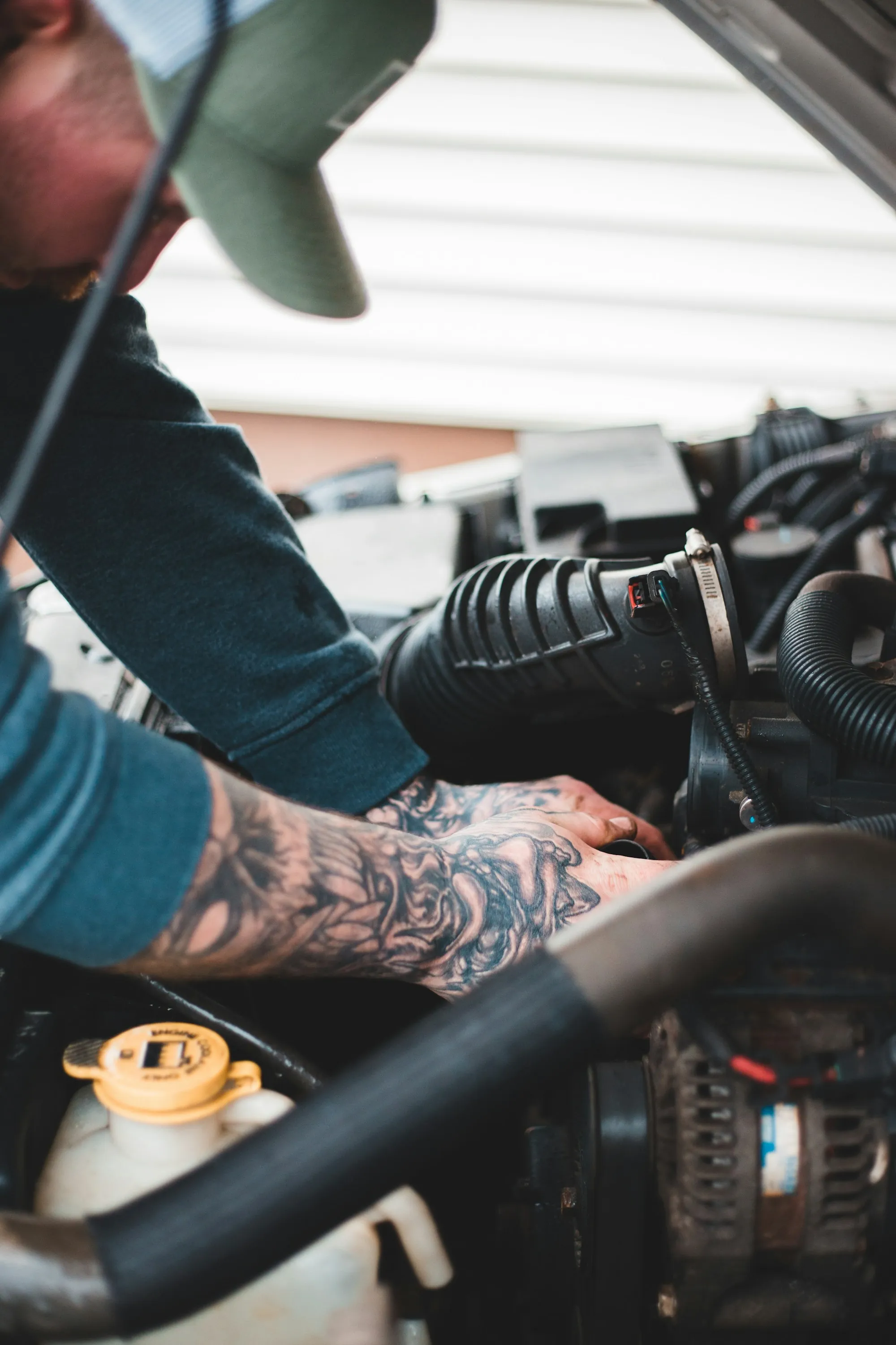 Mechanic in work gloves reaching into an engine compartment
