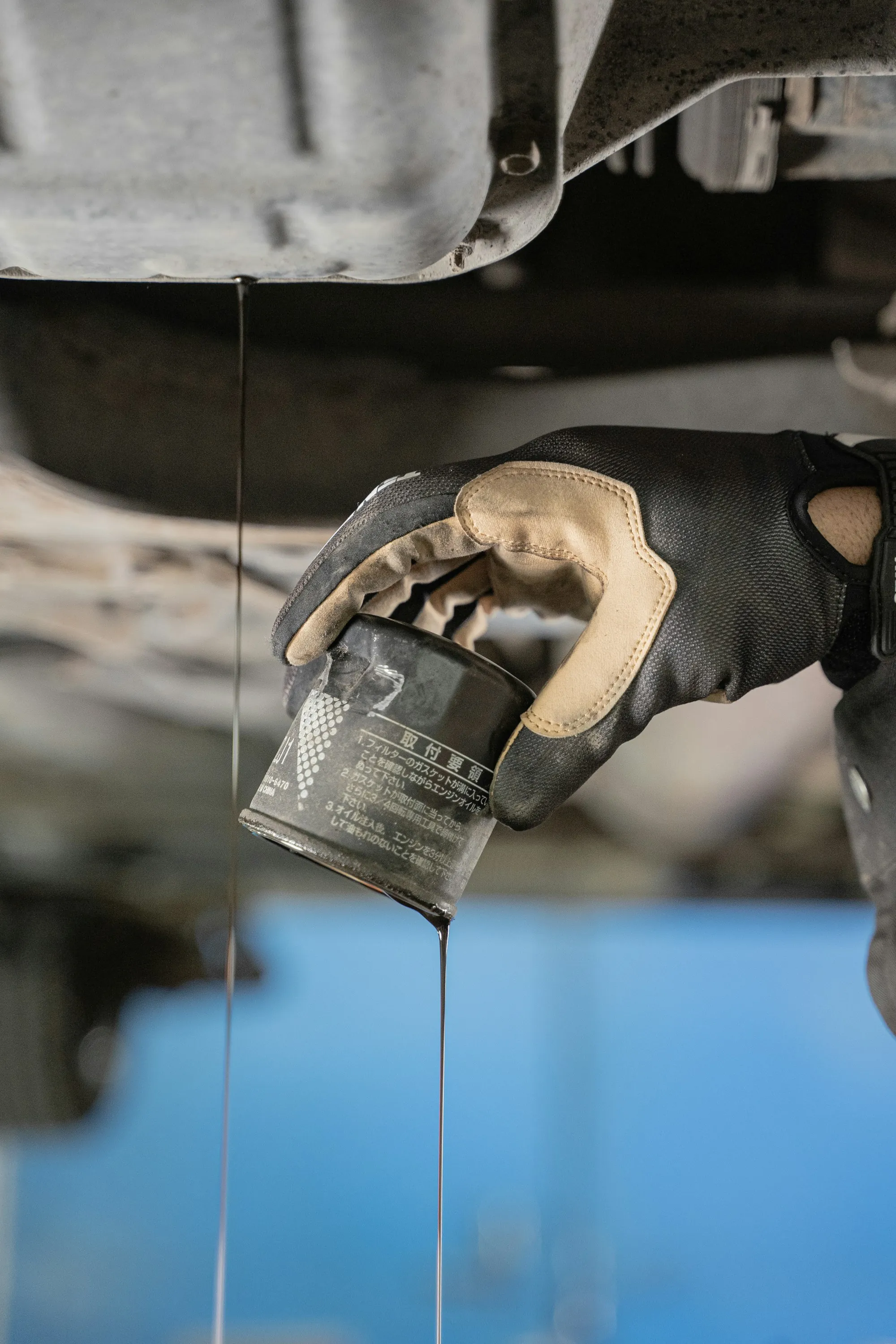 Mechanic in gloves removing a used oil filter