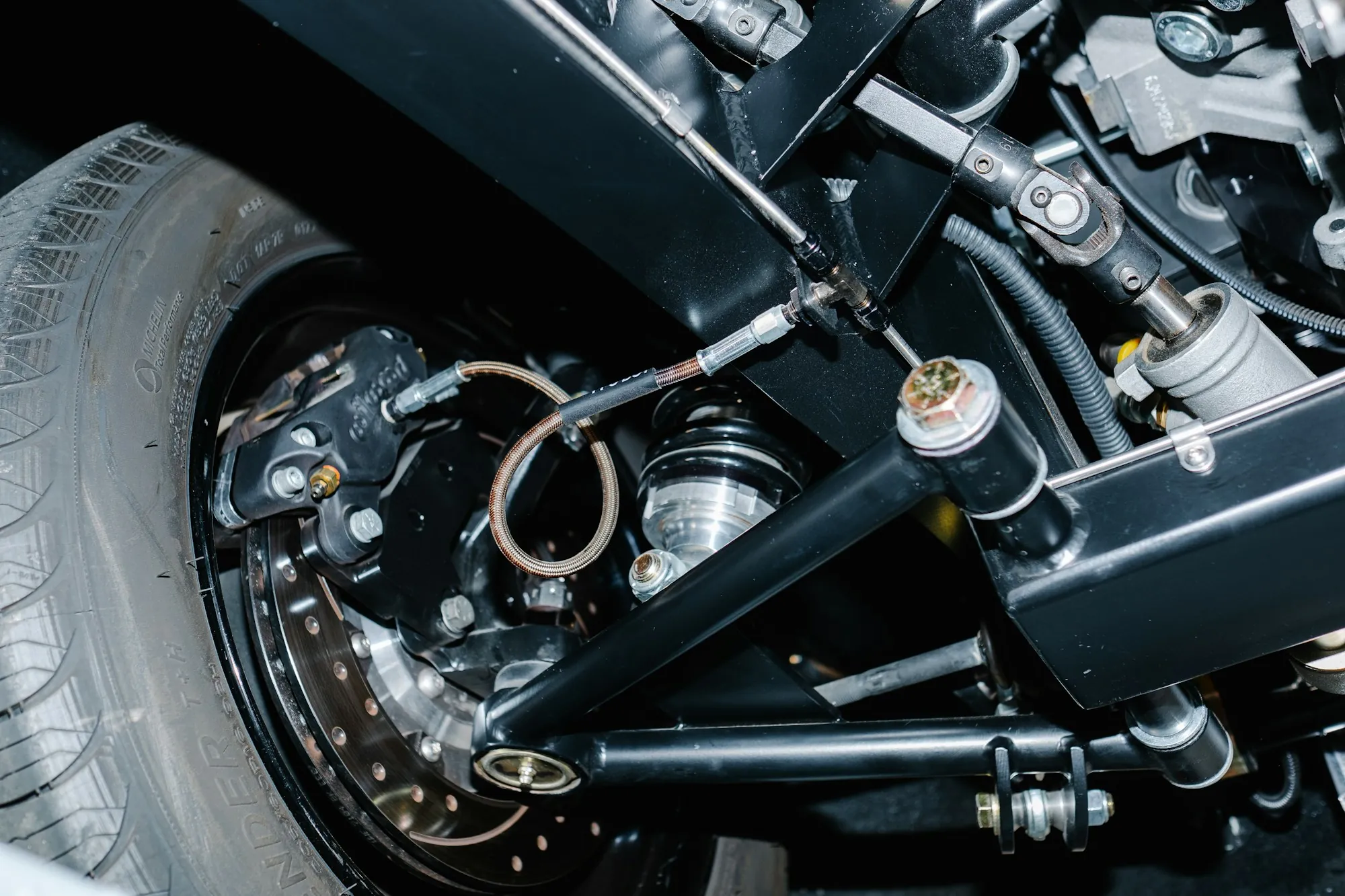 Front suspension assembly and brake disc visible under a car